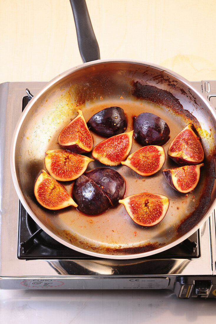 Quartered common figs being fried in pan