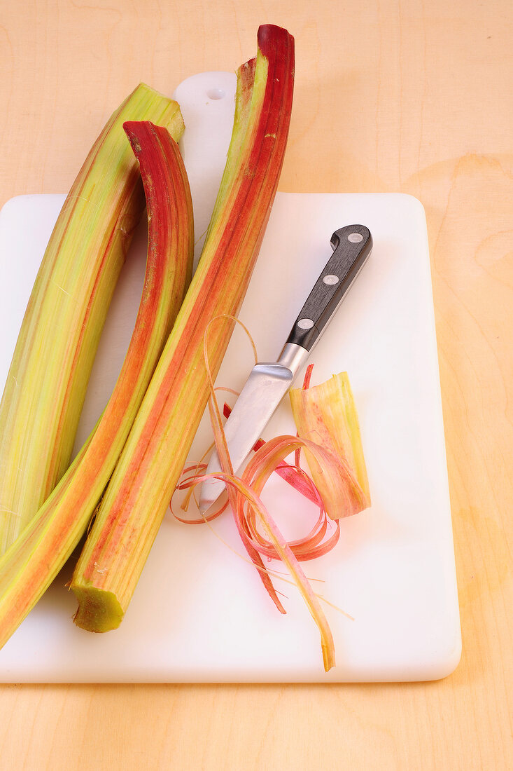Peeled red rhubarb on chopping board for preparation of desserts, step 1