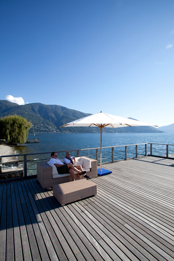 Man and woman sitting on terrace of Eden Roc hotel in Ascona near Lago Maggiore lake