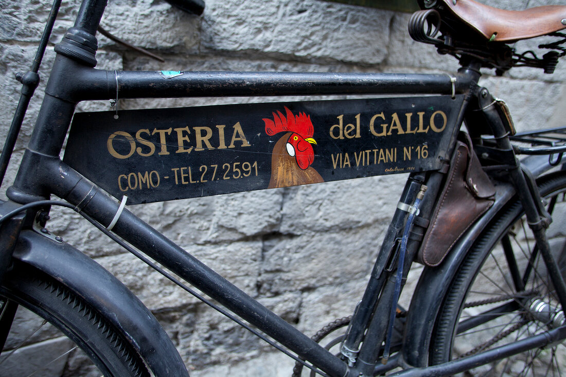 Close-up of bicycle with advertising sign, Como, Lombardy, Italy