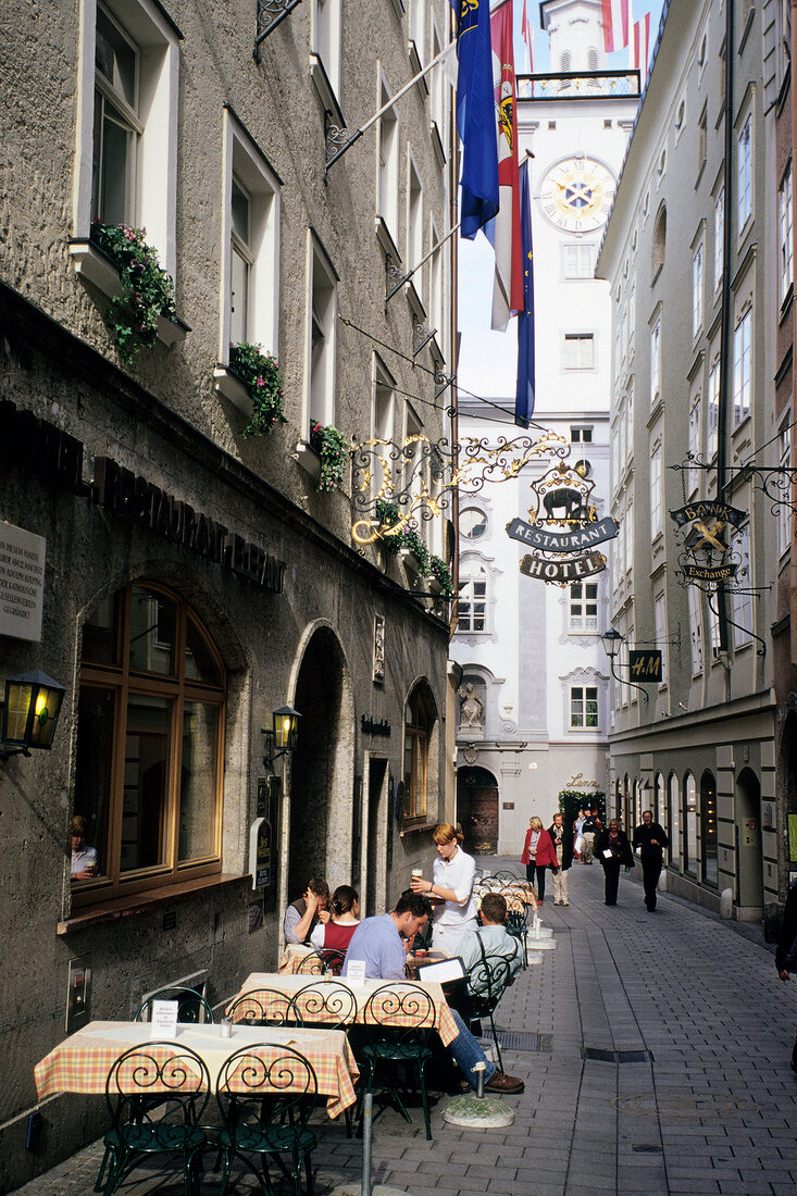 People sitting in outdoors cafe in an alley of old town, Salzburg, Austria