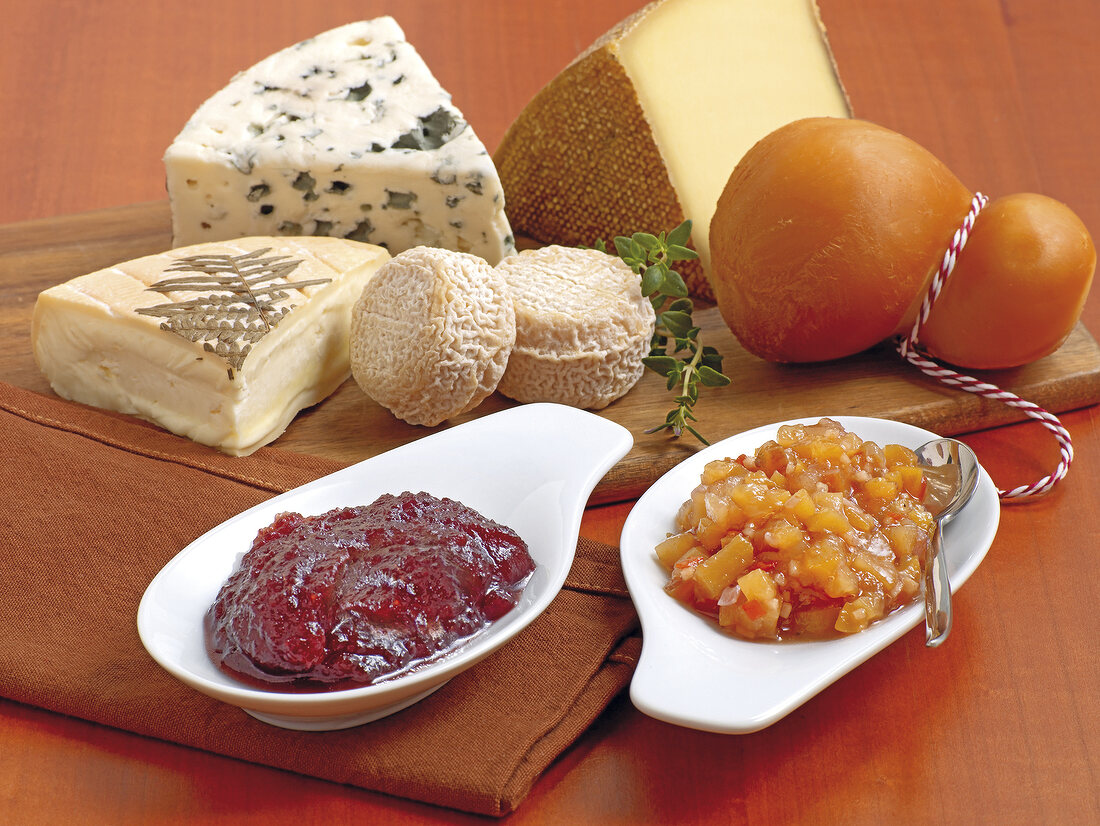 Various types of chutney and cheeses on wooden surface