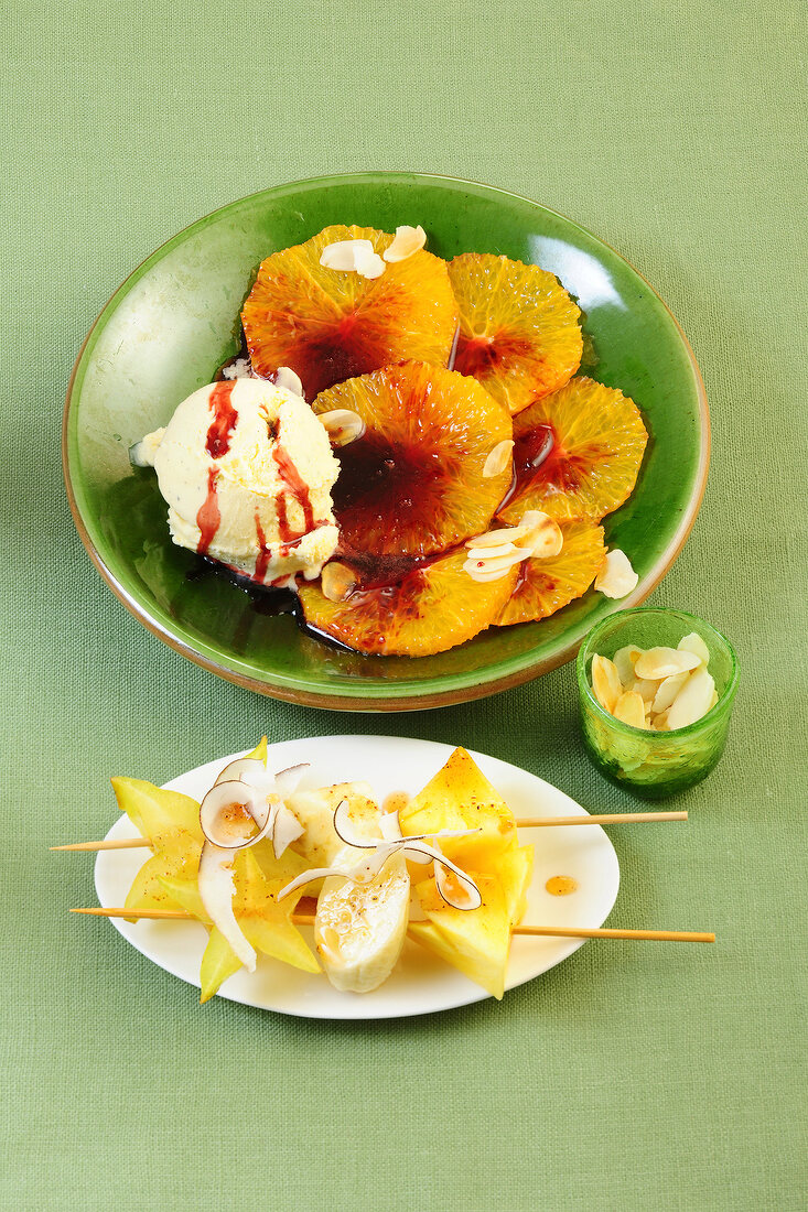 Orange carpaccio in bowl and fruit skewers on plate
