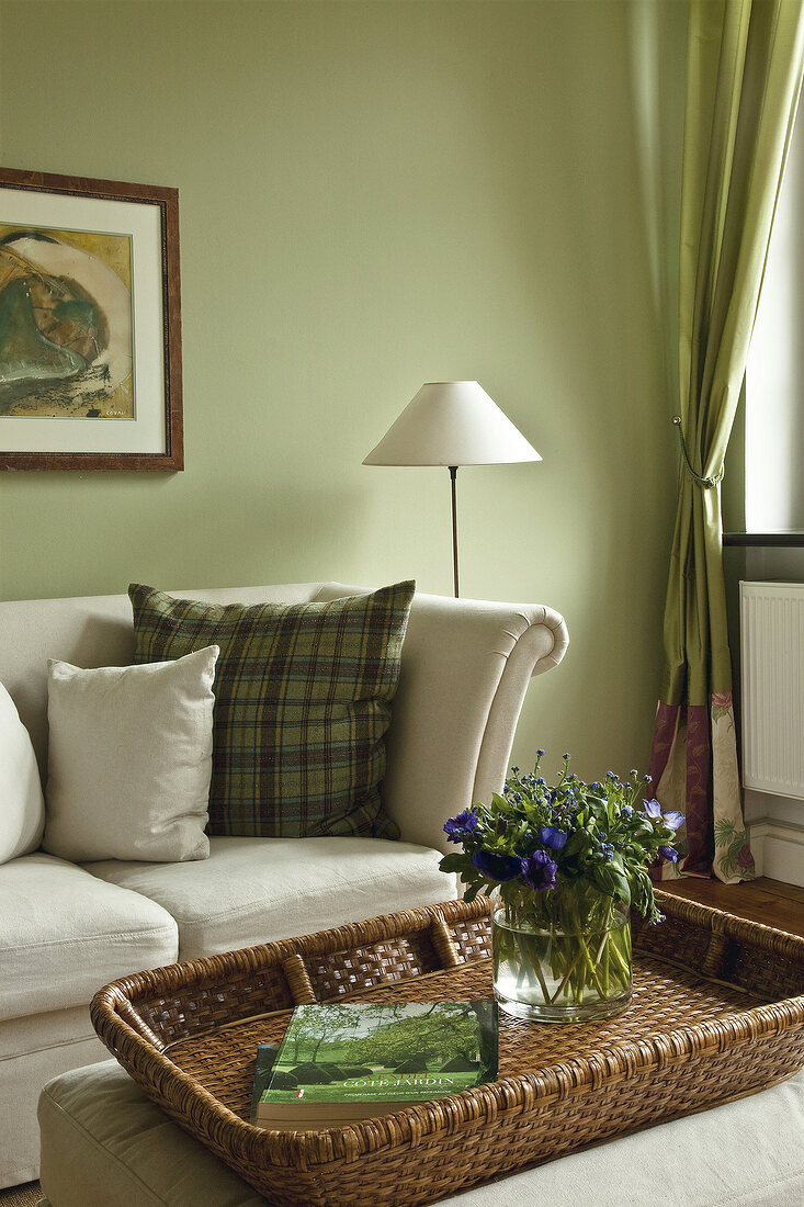 Creme sofa with patterned cushions and wicker basket with flower vase in living room