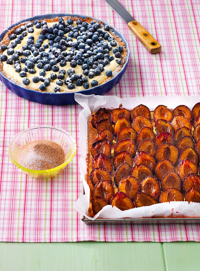 Blueberry tart and plum cake in baking sheet