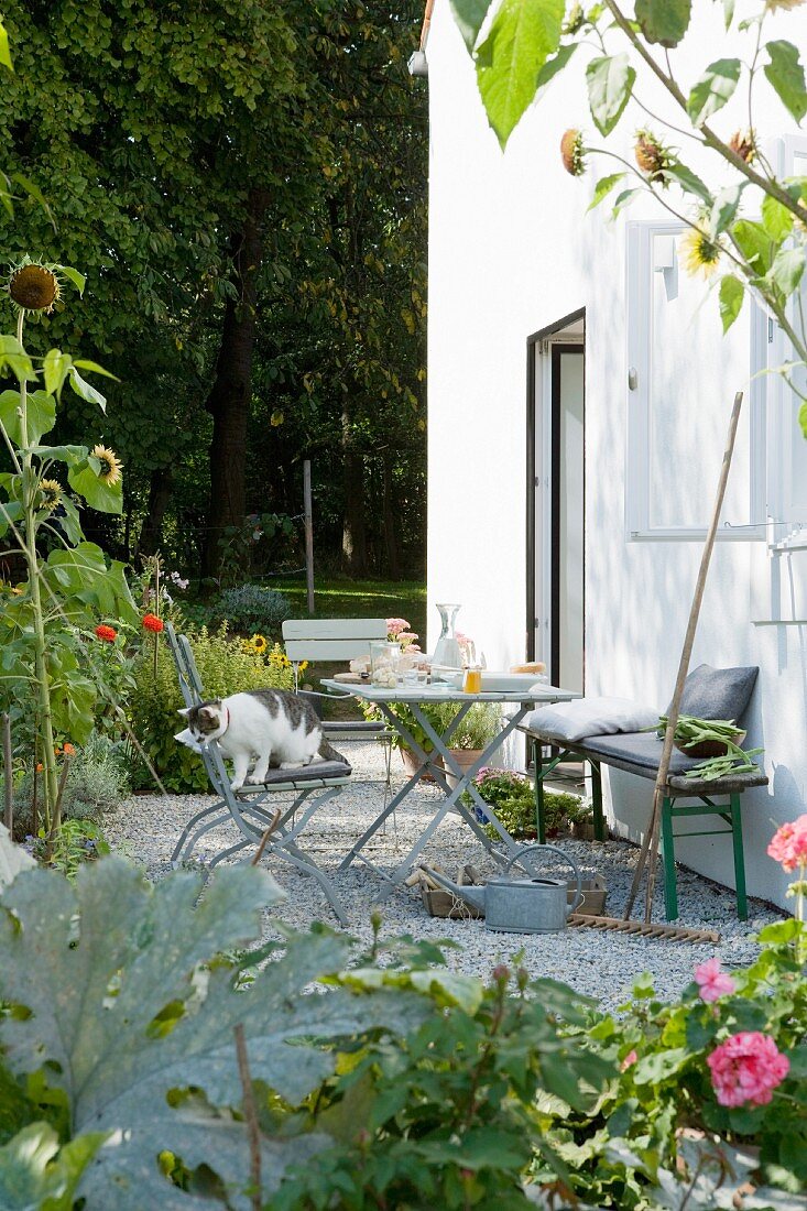 Small table, chairs and bench against house facade in garden