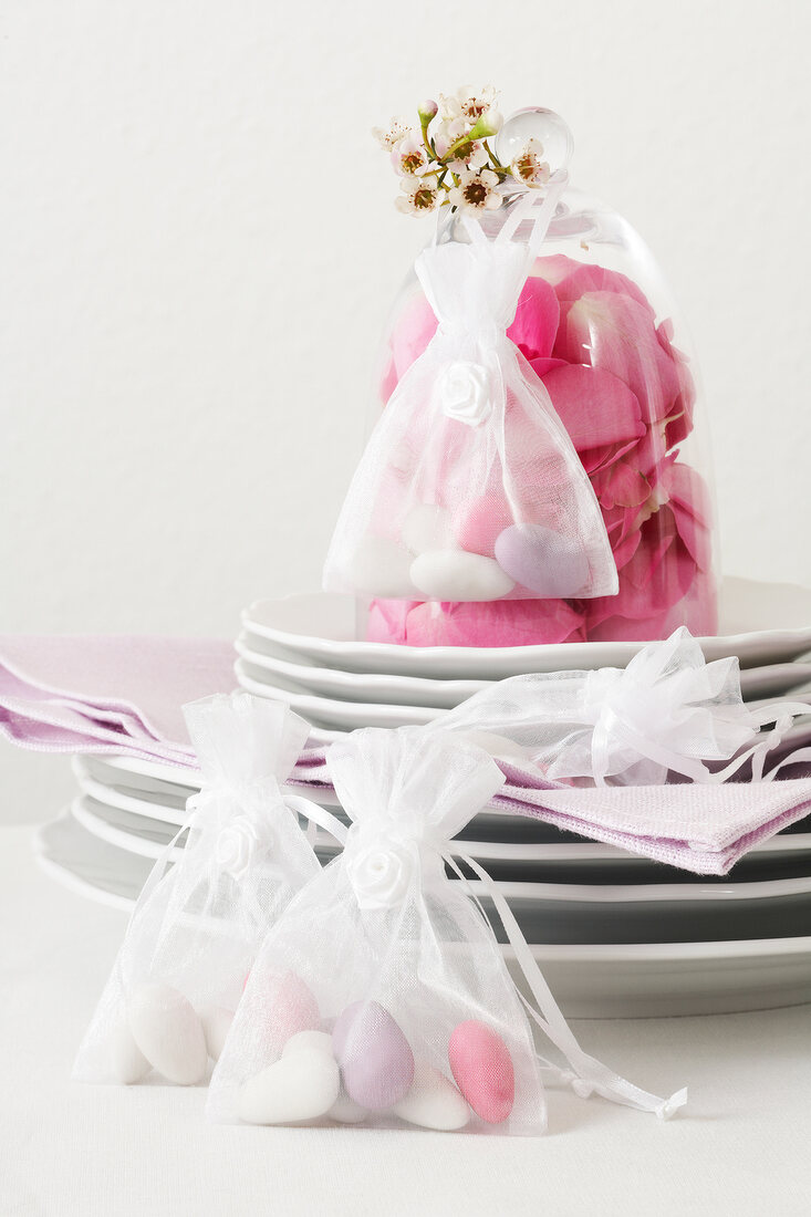 Organza bag with wedding almonds on stack of plates