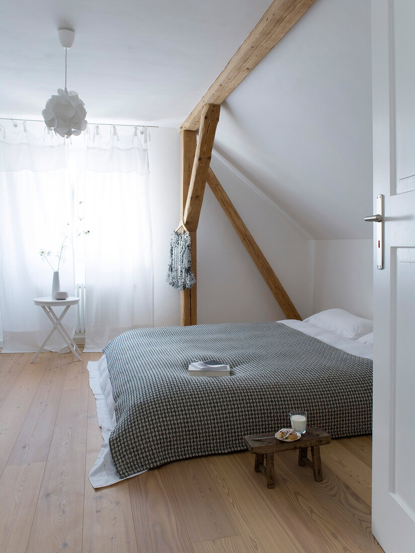 Bed and small stool under pitched roof