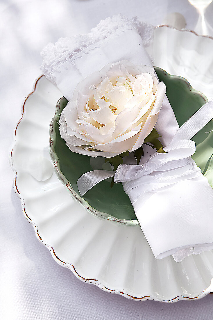 weiße Rose und Serviette auf weißem Teller