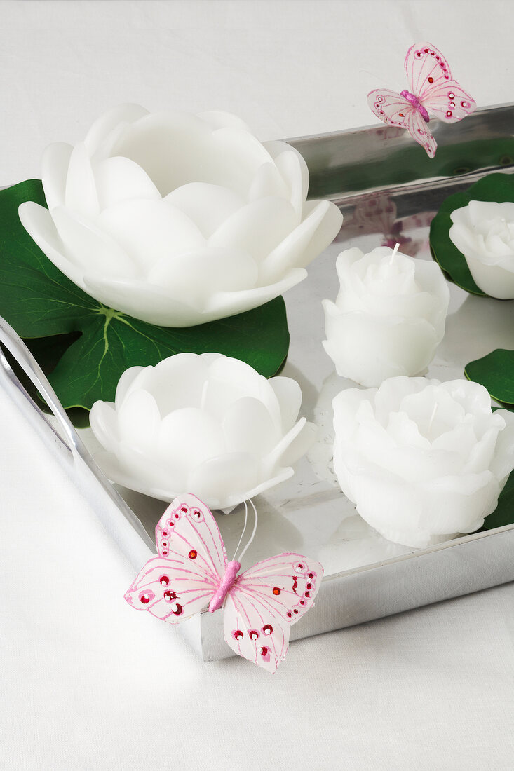 White floating candles and paper butterflies on tray