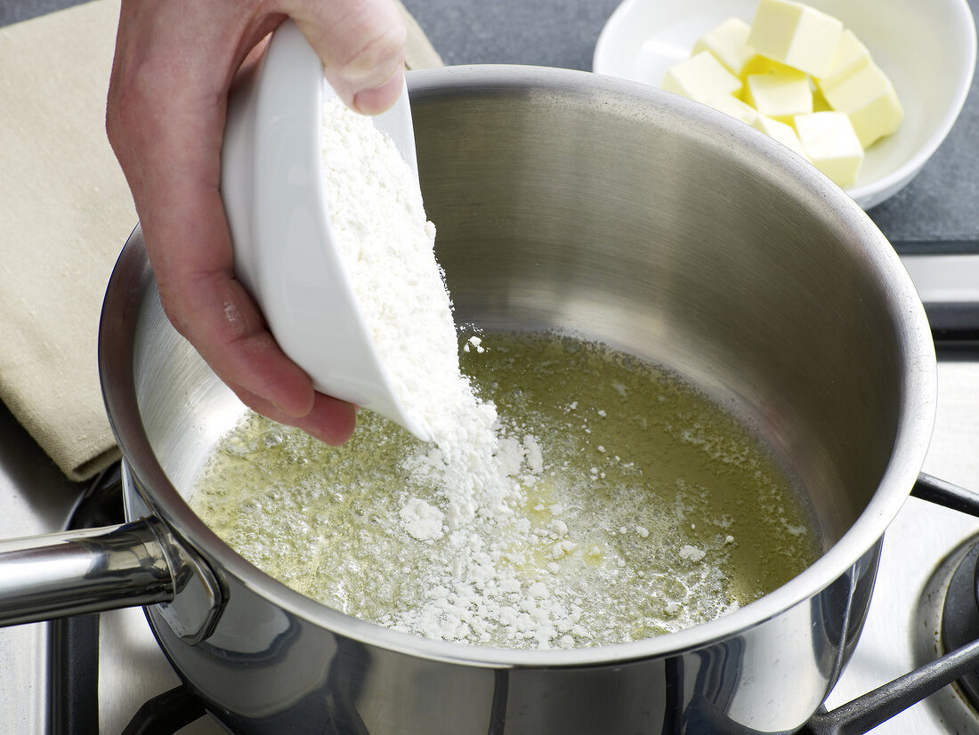 Flour being added in saucepan for preparation of bechamel sauce, step 1