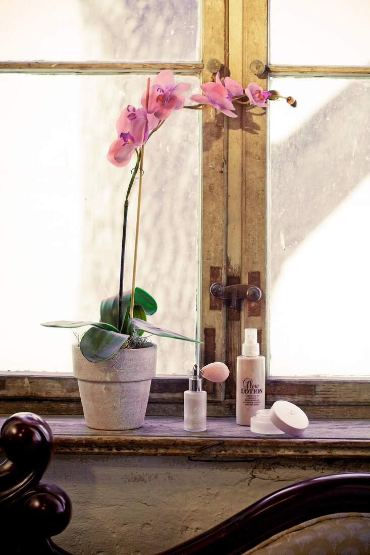 Cosmetics on window sill next to orchid