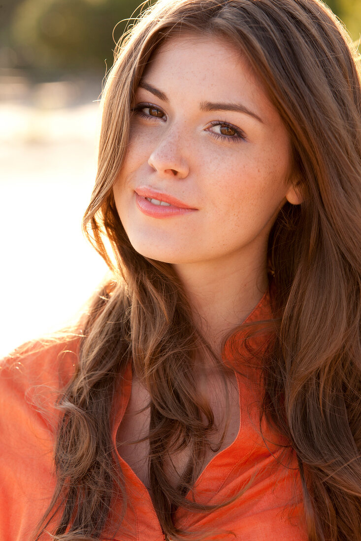 Portrait of beautiful woman with brown hair wearing orange top