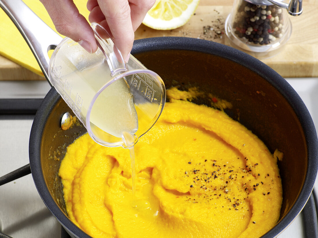 Lime juice being poured to carrot coulis in sauce pan, step 4