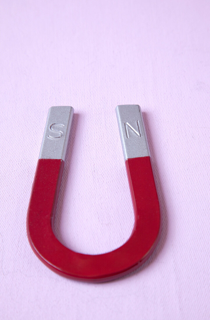 Close-up of horseshoe magnet on pink background