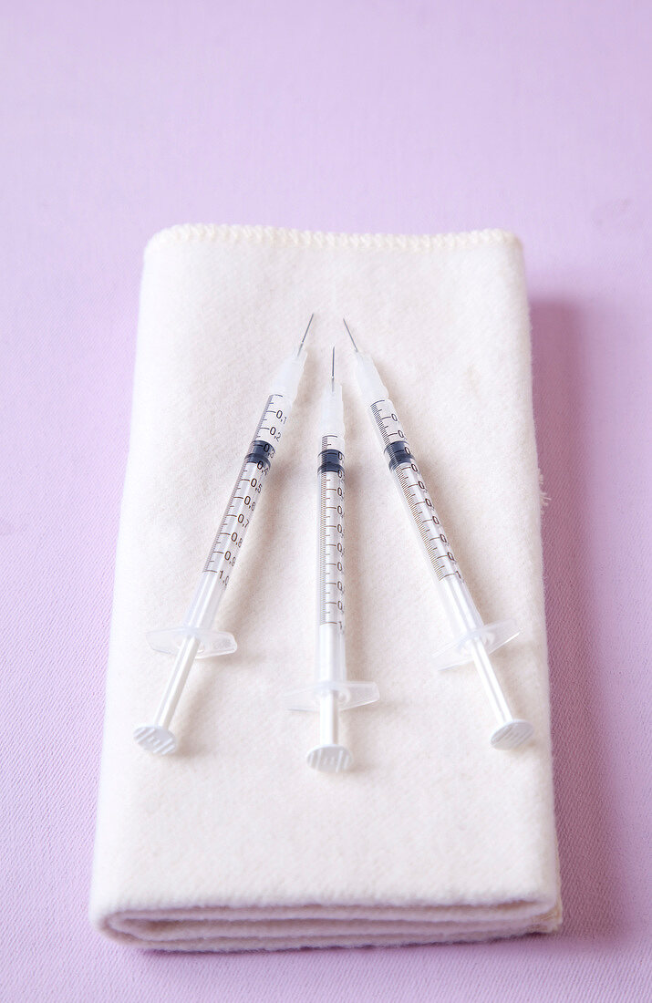Close-up of three syringes on white napkin