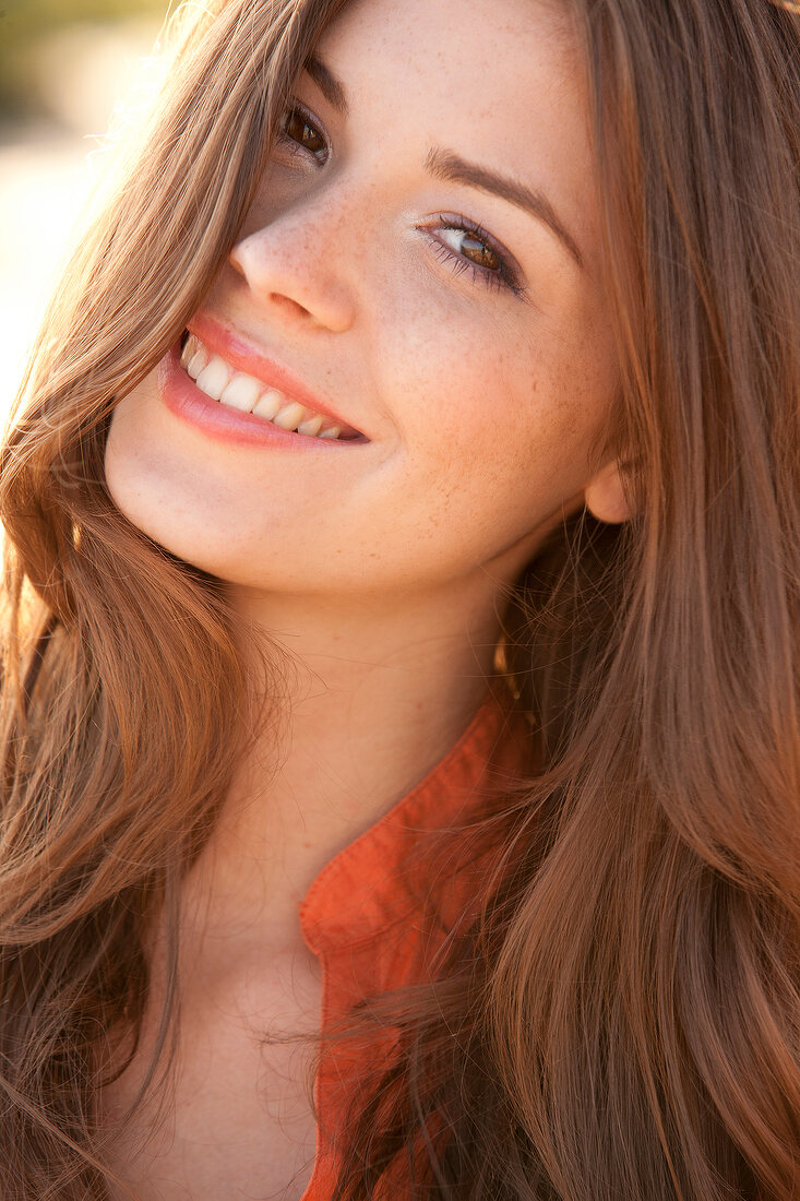 Portrait of beautiful woman with brown hair wearing orange top