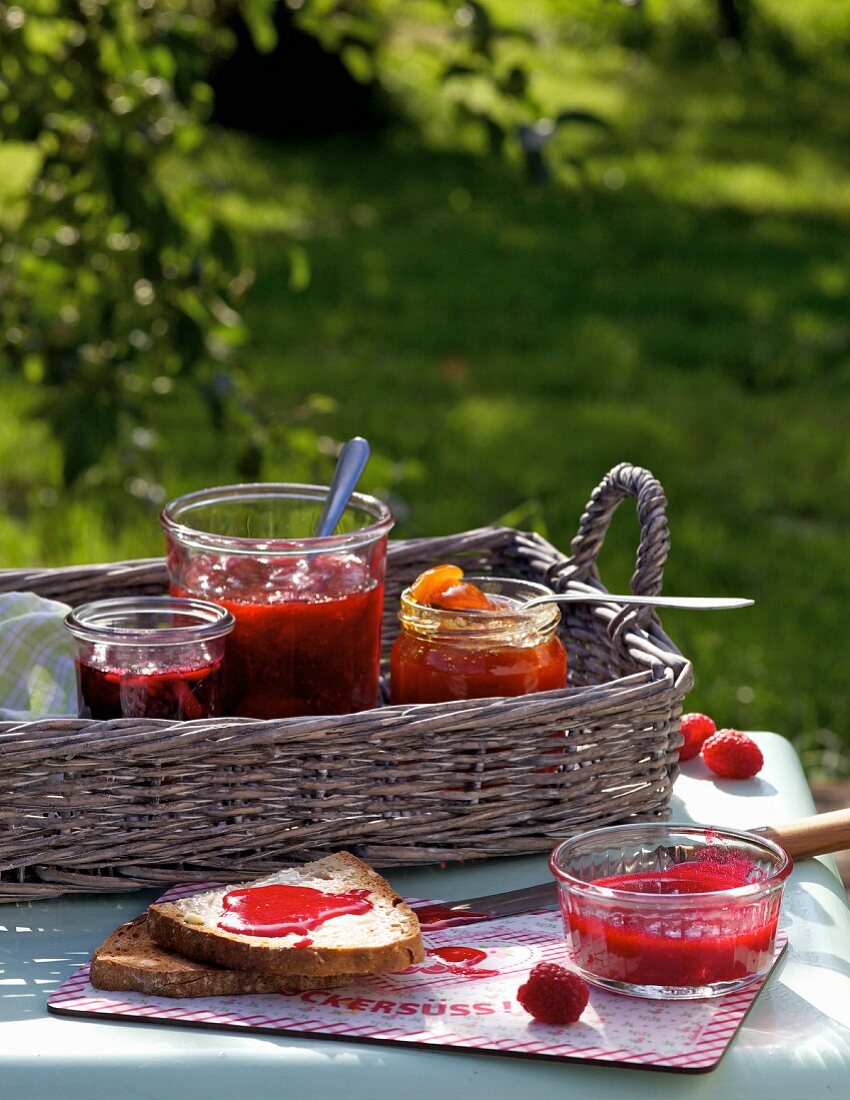Various jars of homemade jam on a tray on a table outside