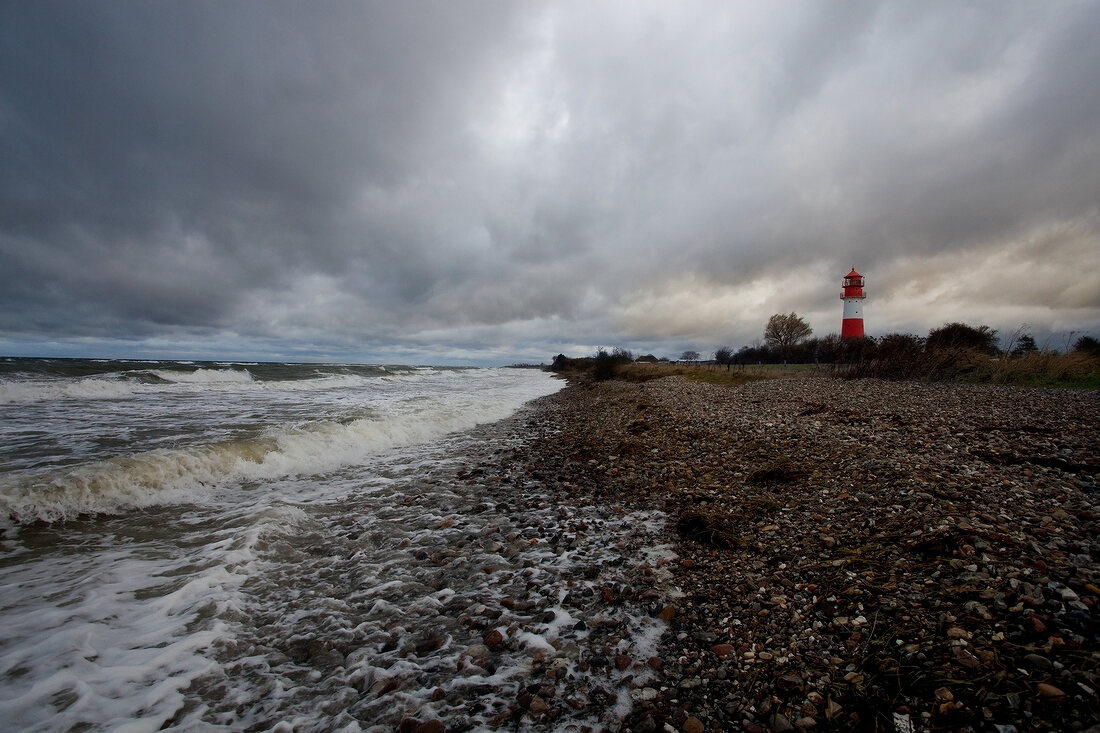 View of lighthouse with stones on beach at Baltic Sea Coast