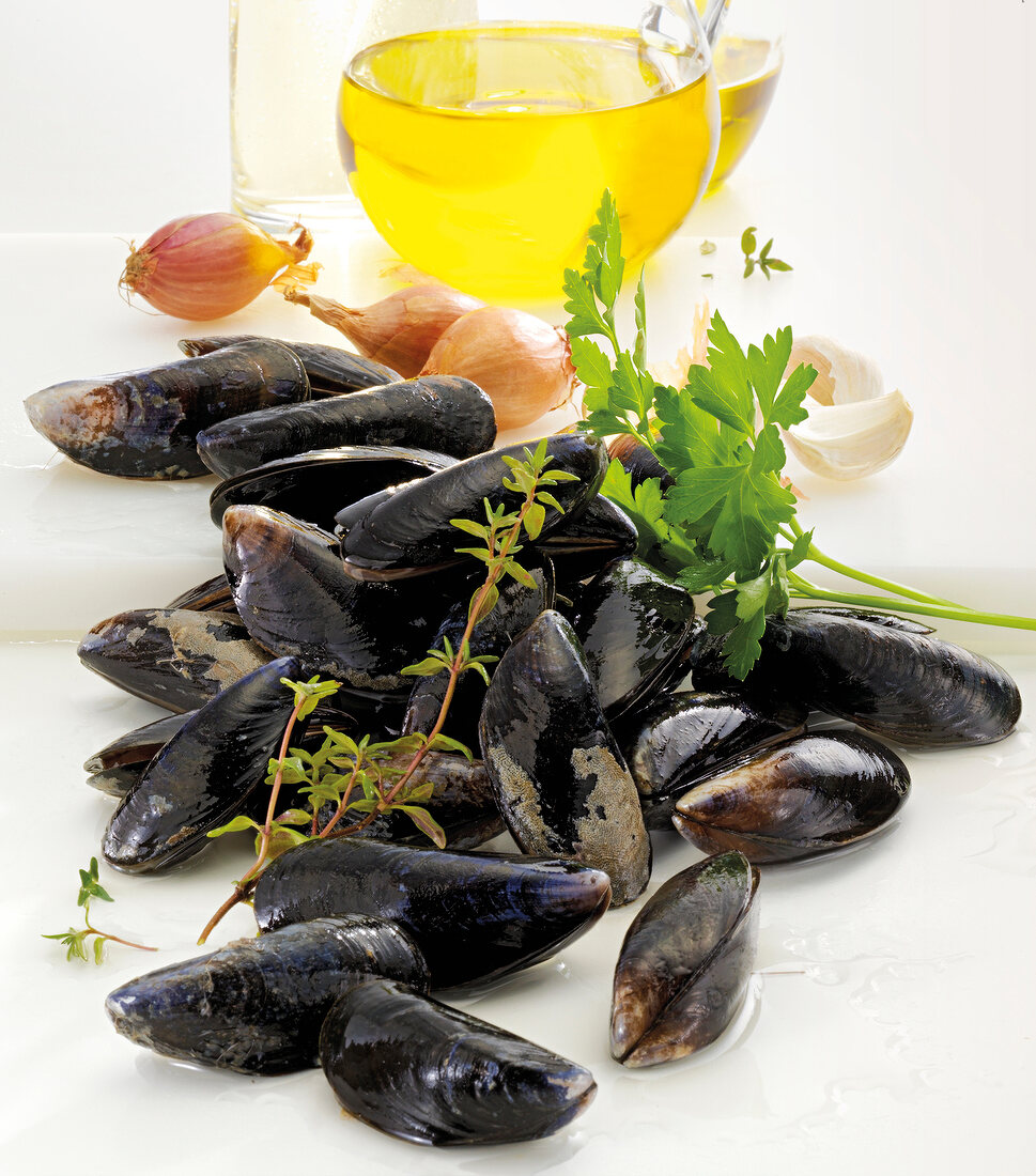 Close-up of mussels, shallots oil and herbs on white background