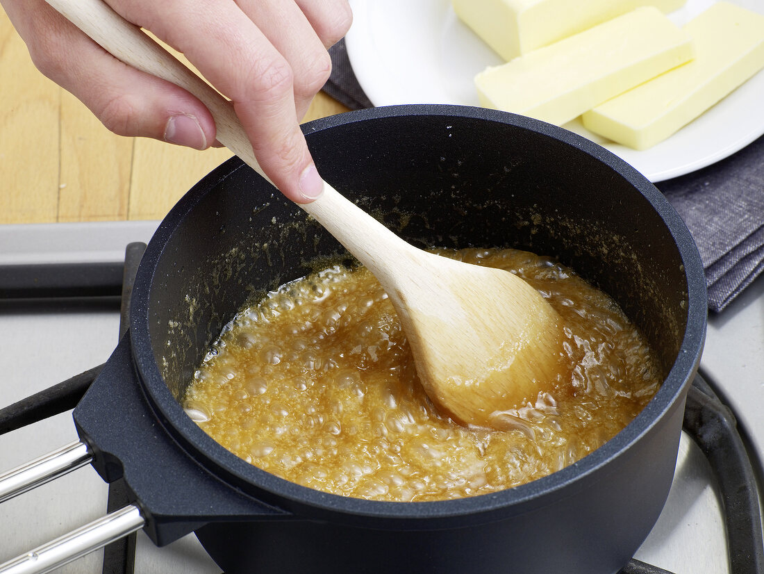 Boiling sugar being stirred for preparation of caramel sauce, step 1