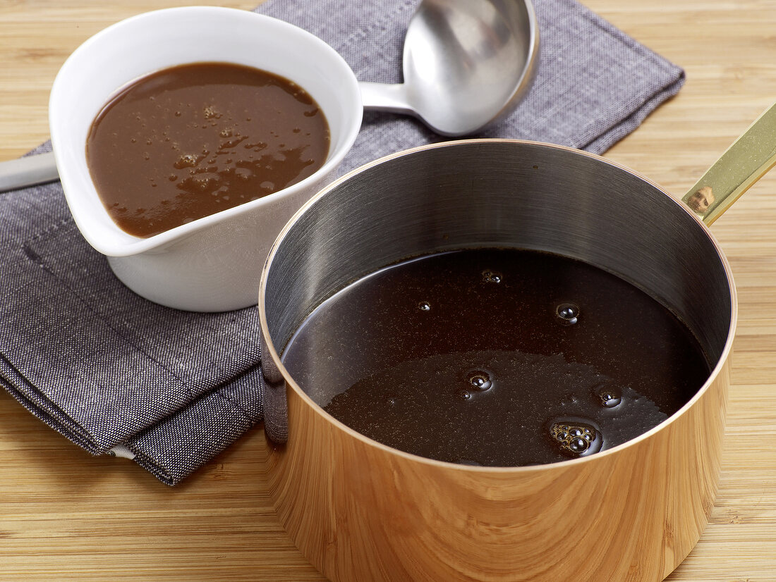 Dark coloured sauces in serving dish and saucepan