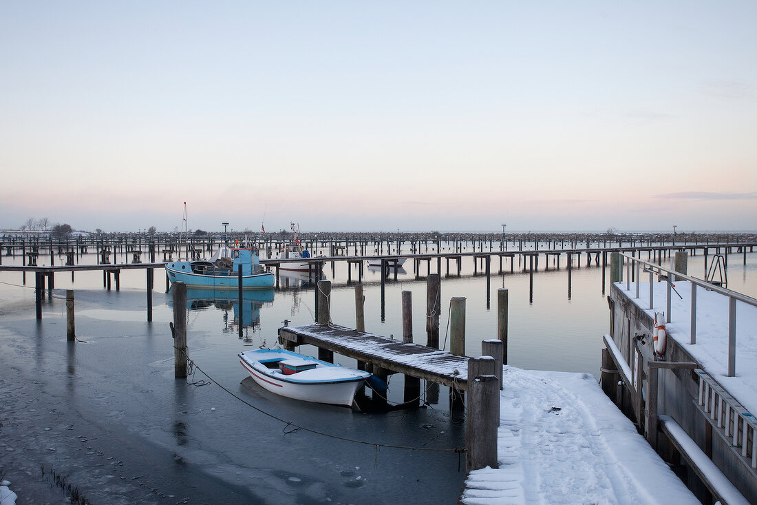 Fishing boats moored at frozen water at Gelting at Schleswig-Holstein, Germany