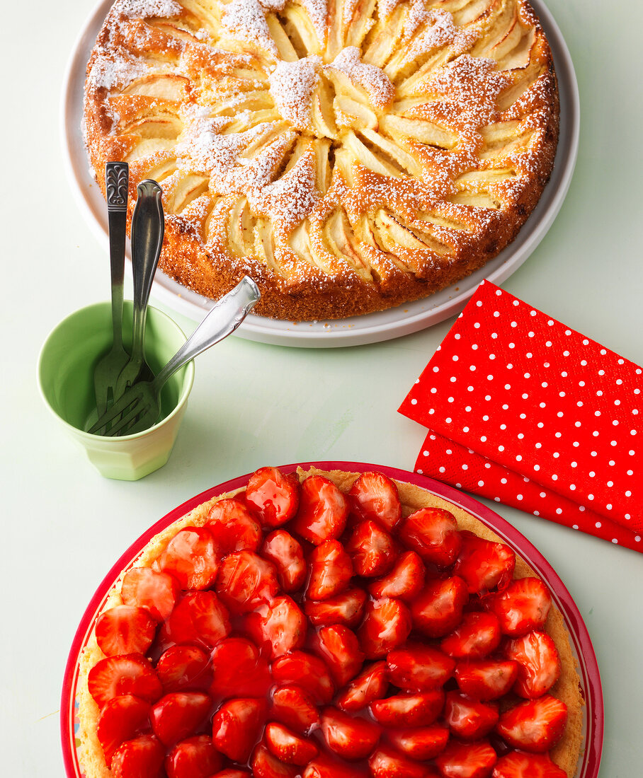 Sunken apple cake with icing sugar and strawberry cake on plate 