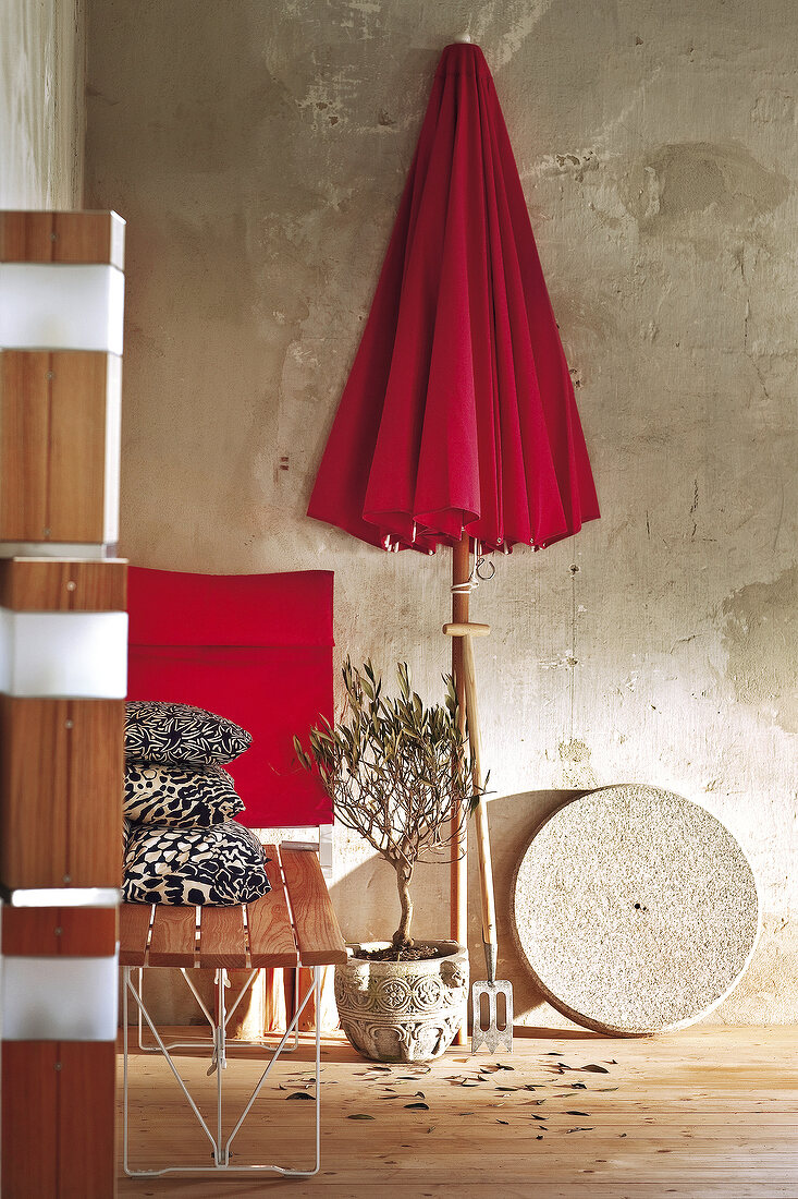 Red umbrella, cushions and table as garden furniture inside room