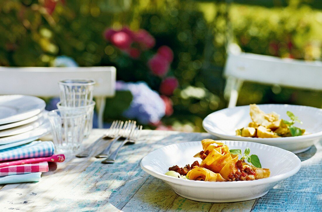 Pappardelle mit Hühnerbolognese auf Tisch im Freien