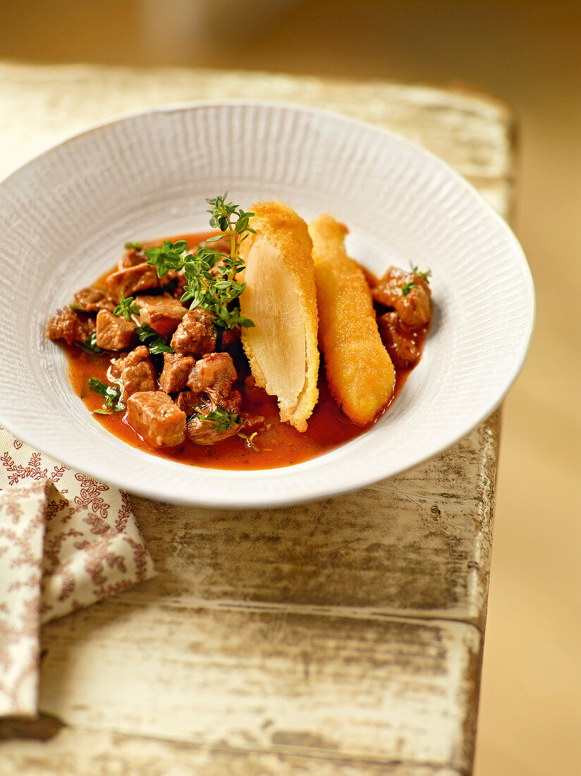 Veal stew with salsify in serving bowl, garden kitchen