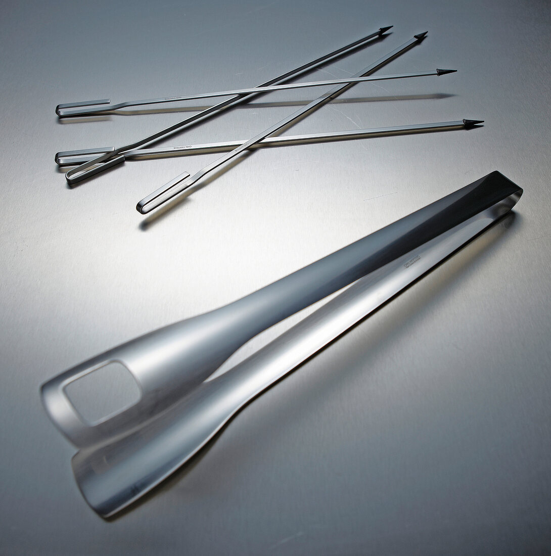 Four stainless steel skewers and tongs