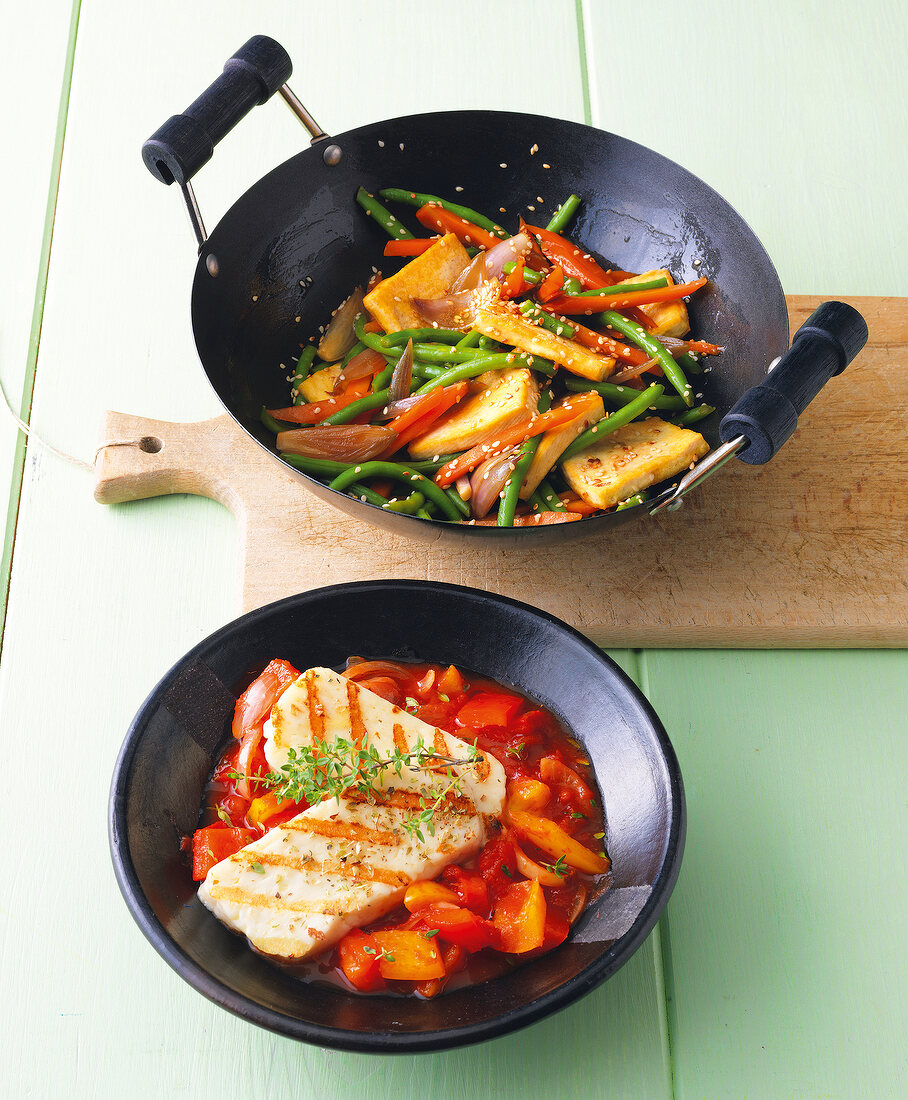Stir fry beans with tofu in wok and halloumi with peperonata in bowl