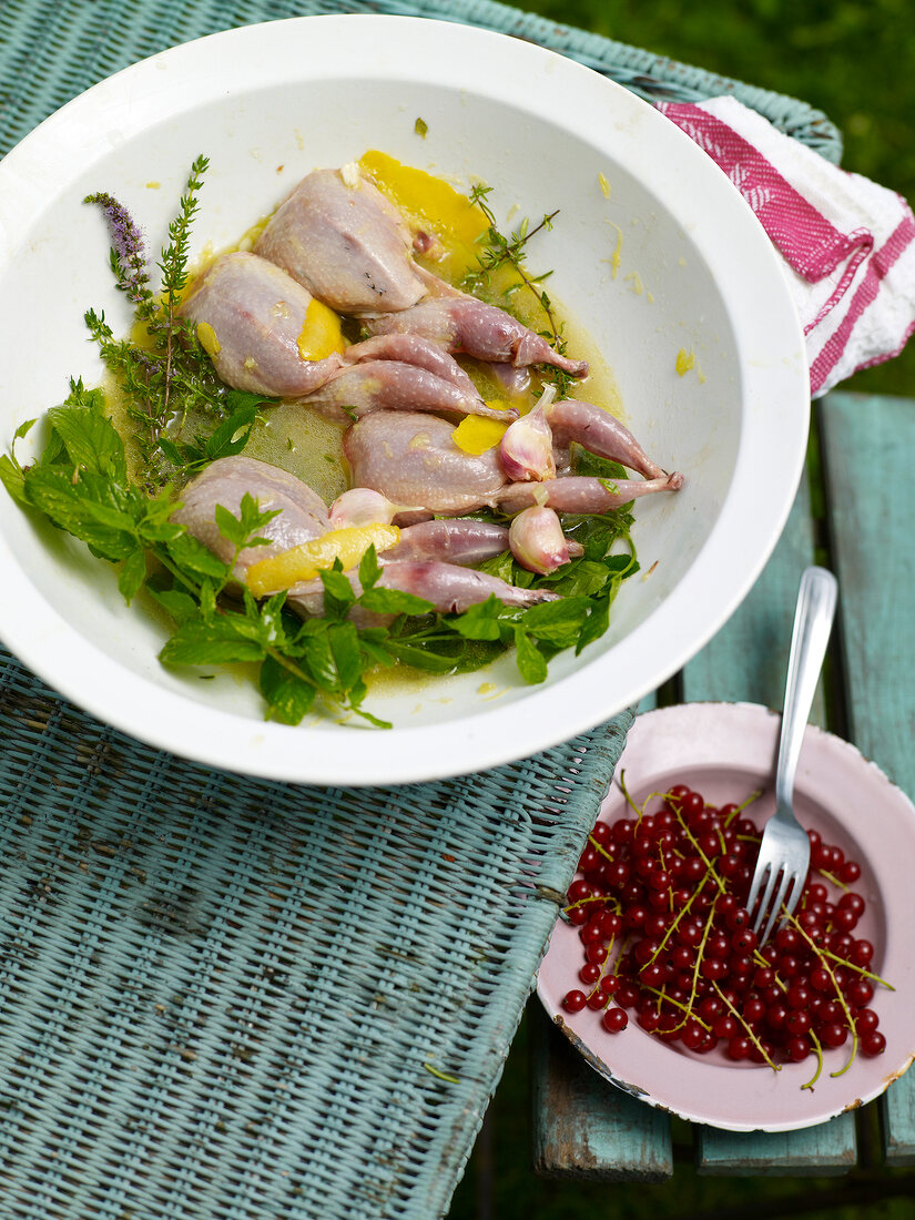 Bowl of marinated quail and cheery on plate