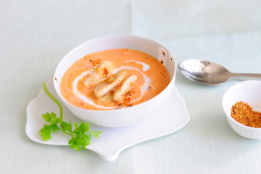 Coconut and tomato soup with chicken strips in bowl