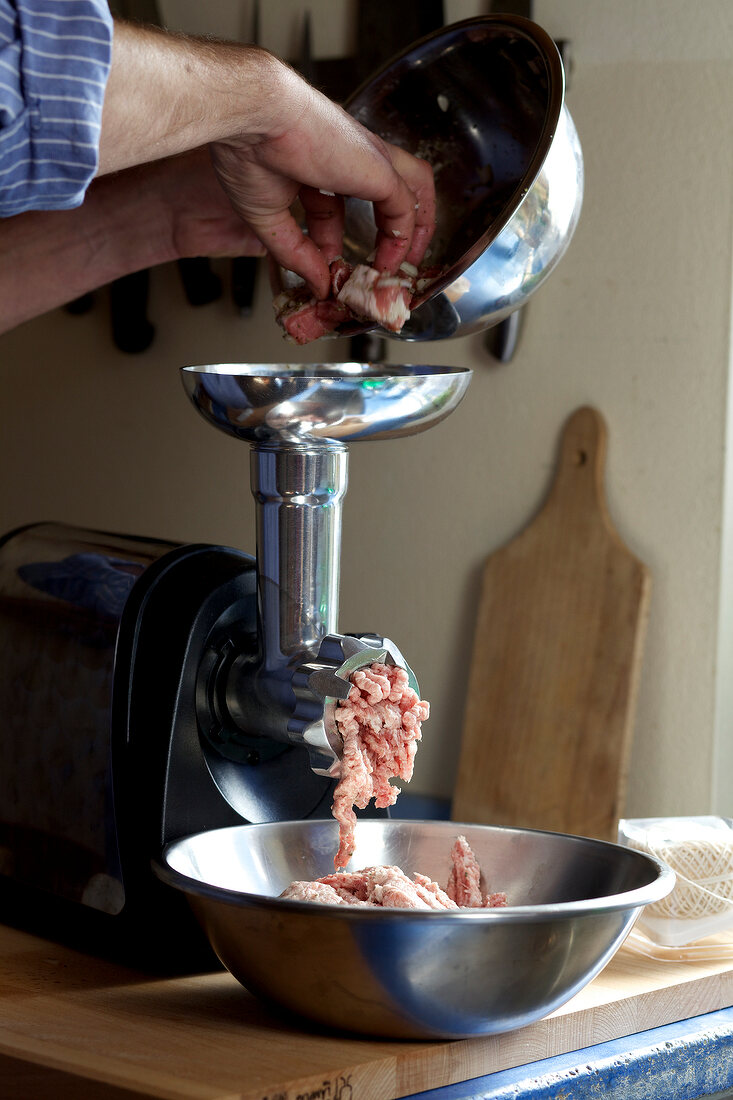 Man grinding meat through meat grinder, step 3