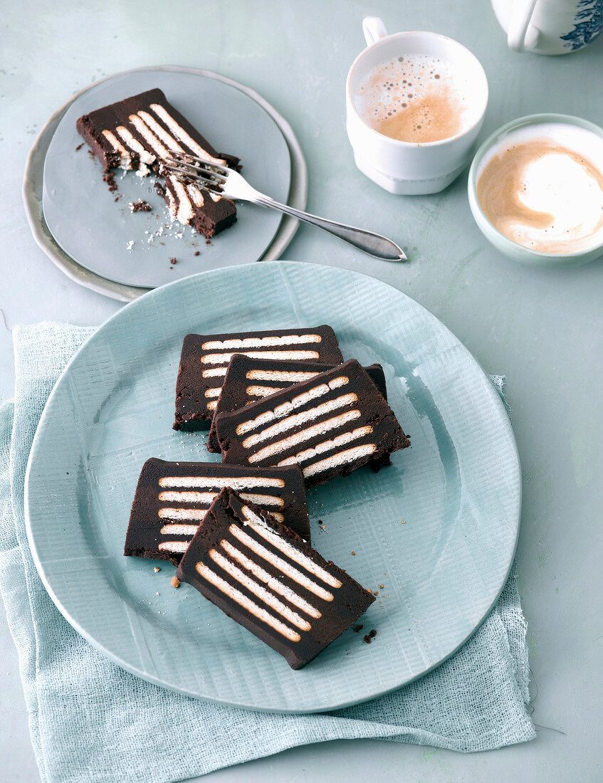 Hedgehog slice on plate next to two cups of cappuccino