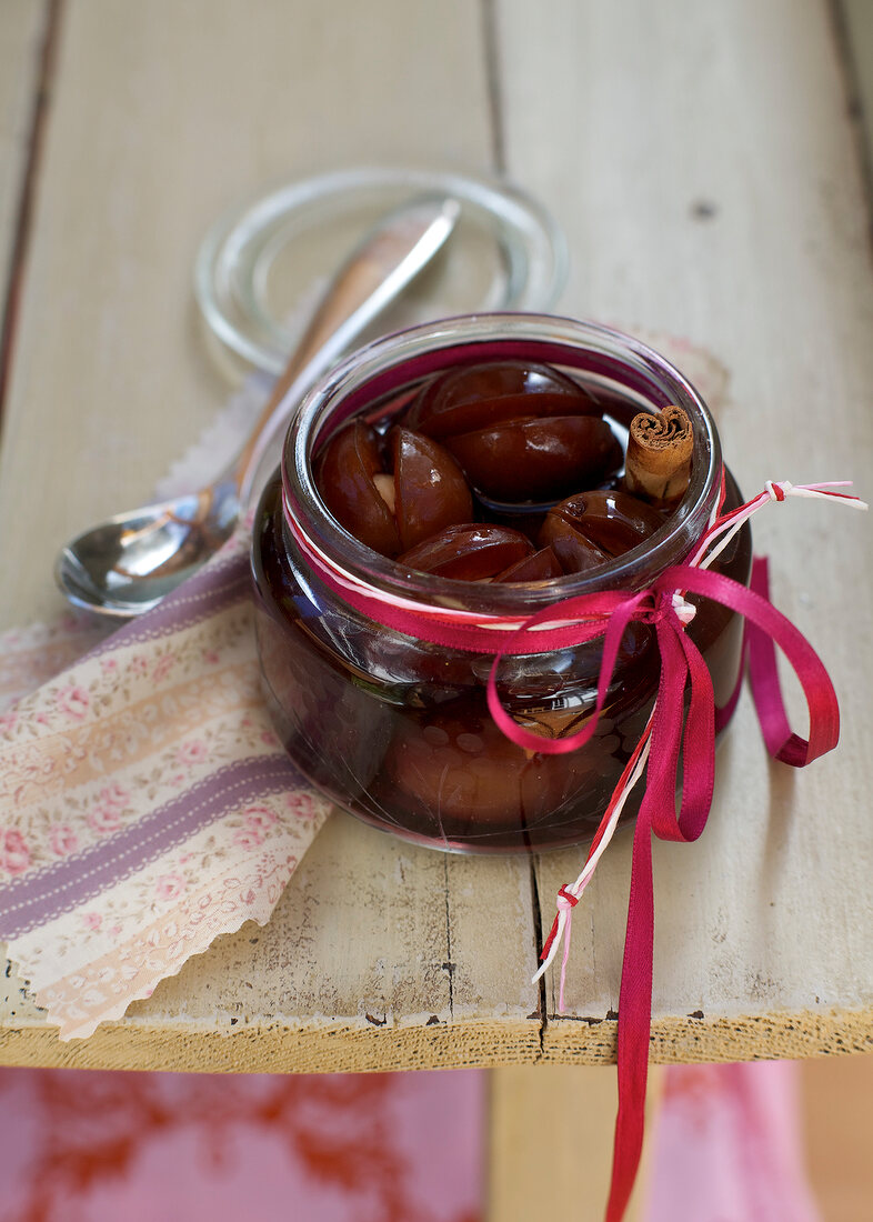 Plums in red wine in glass jar