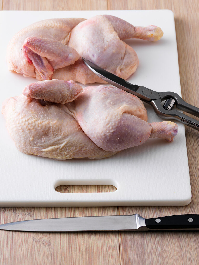 Two whole chicken with poultry shears on chopping board