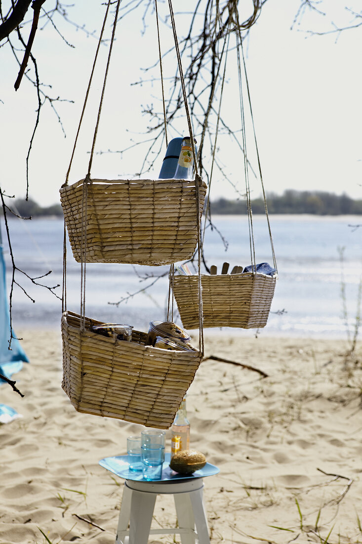 Plate on stool and baskets hanging on tree at beach