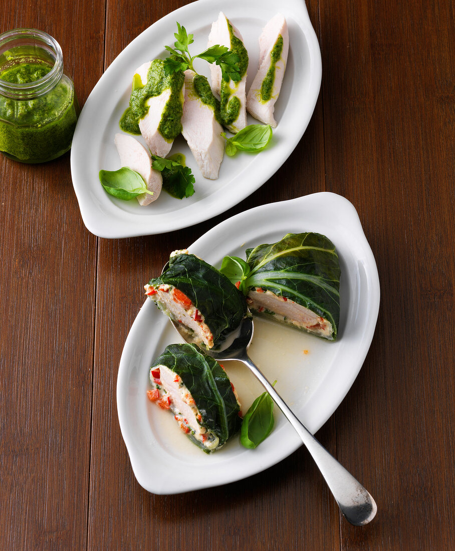 Two serving dishes with poached chicken breast and chicken in chard leaves