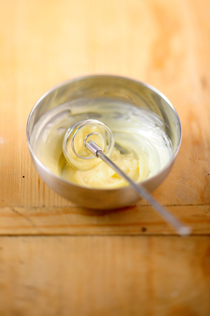 Blended egg yolk and lemon juice with whisk in bowl while preparing mayonnaise, step 1