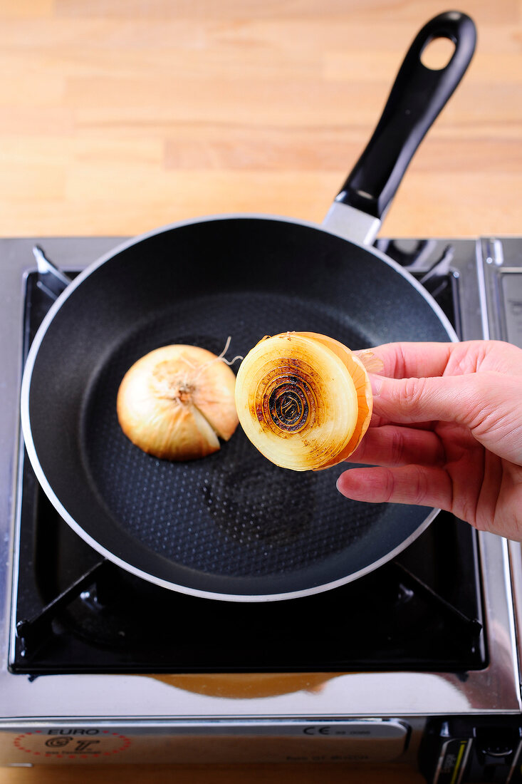 Close-up of hand holding halved fried onion while preparing sauces and dips, step 1