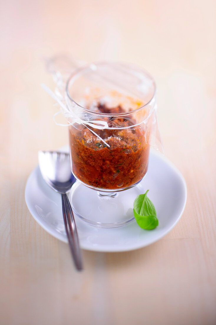 Glass of pesto all�arrabbiata covered with plastic on plate