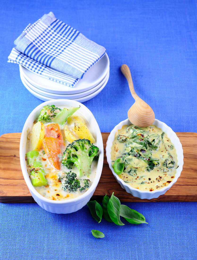 Two different ofengratins with vegetables in bowls
