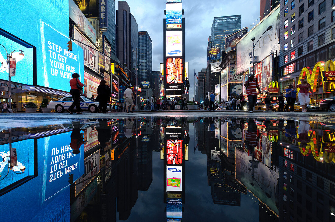 Reflection of illuminated advertisements on puddle at Times Square in New York, USA