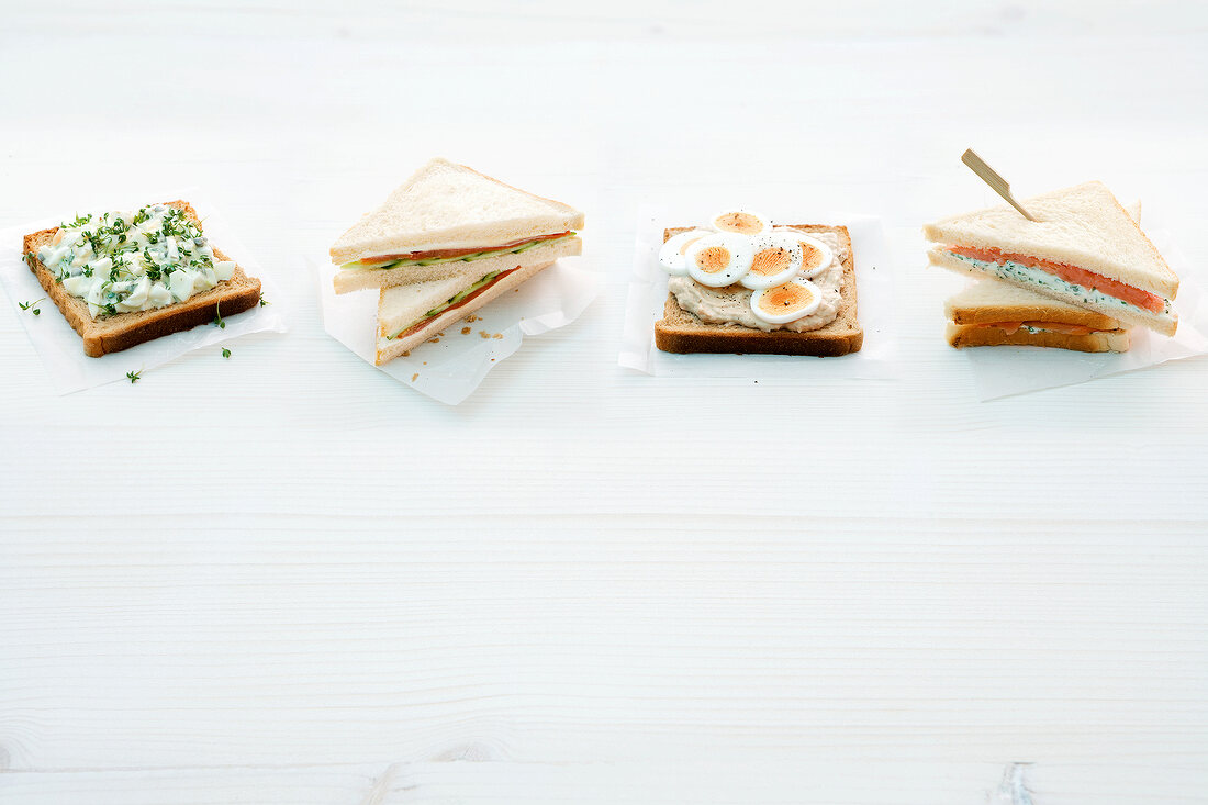 Four different type of tramezzini snacks on white background