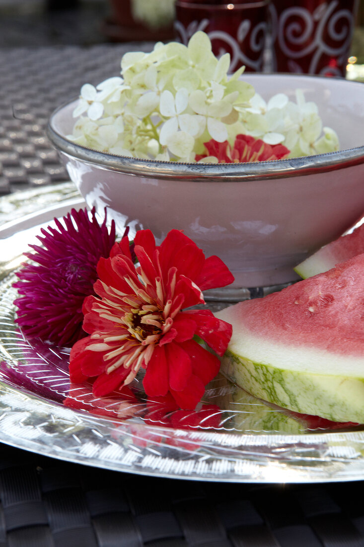 Close-up of watermelon and flowers on silver plate