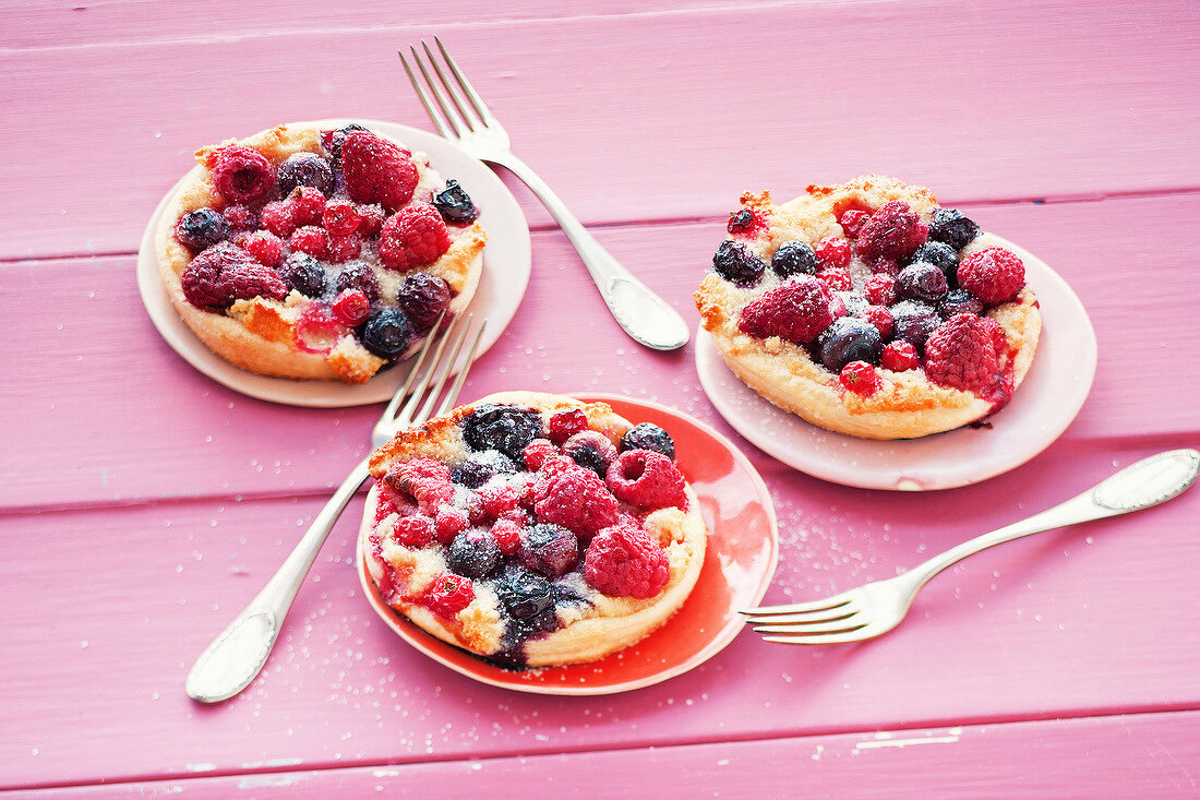 Three plates with berry tart and three forks