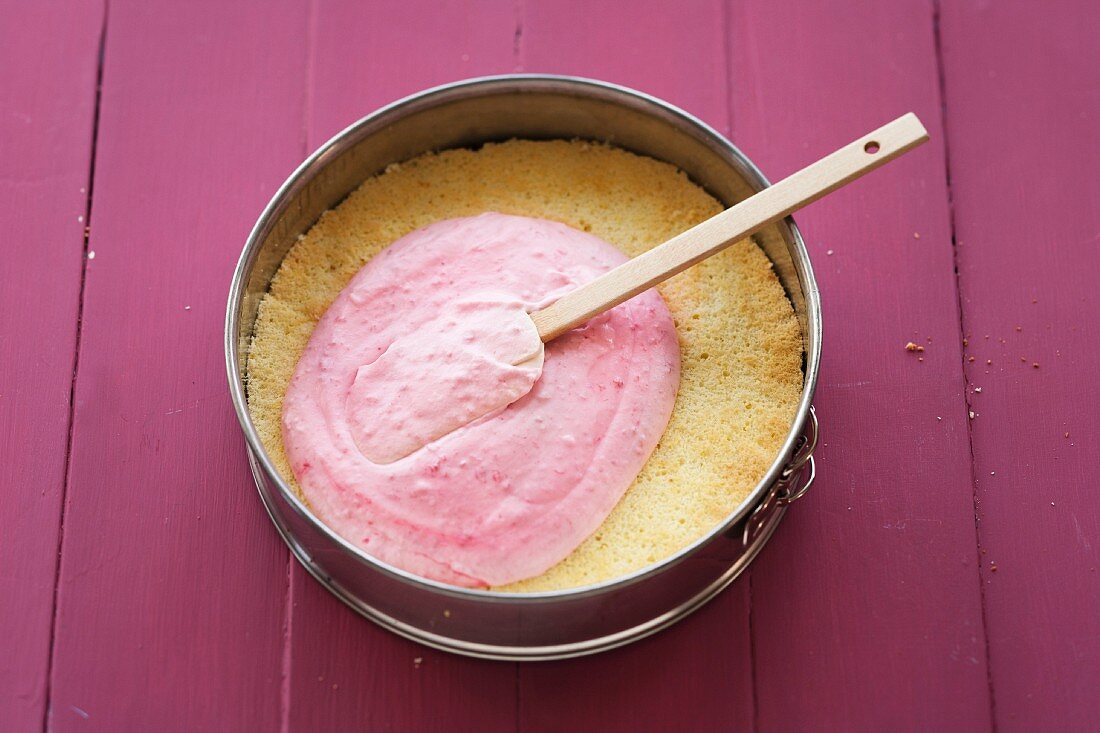 Raspberry cake being made: spreading raspberry sauce onto the base